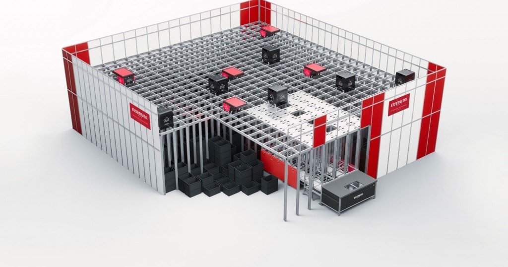 Render de un sistema de almacenamiento de AutoStore con robots rojos en una rejilla superior y contenedores de almacenamiento negros debajo en una estructura modular.