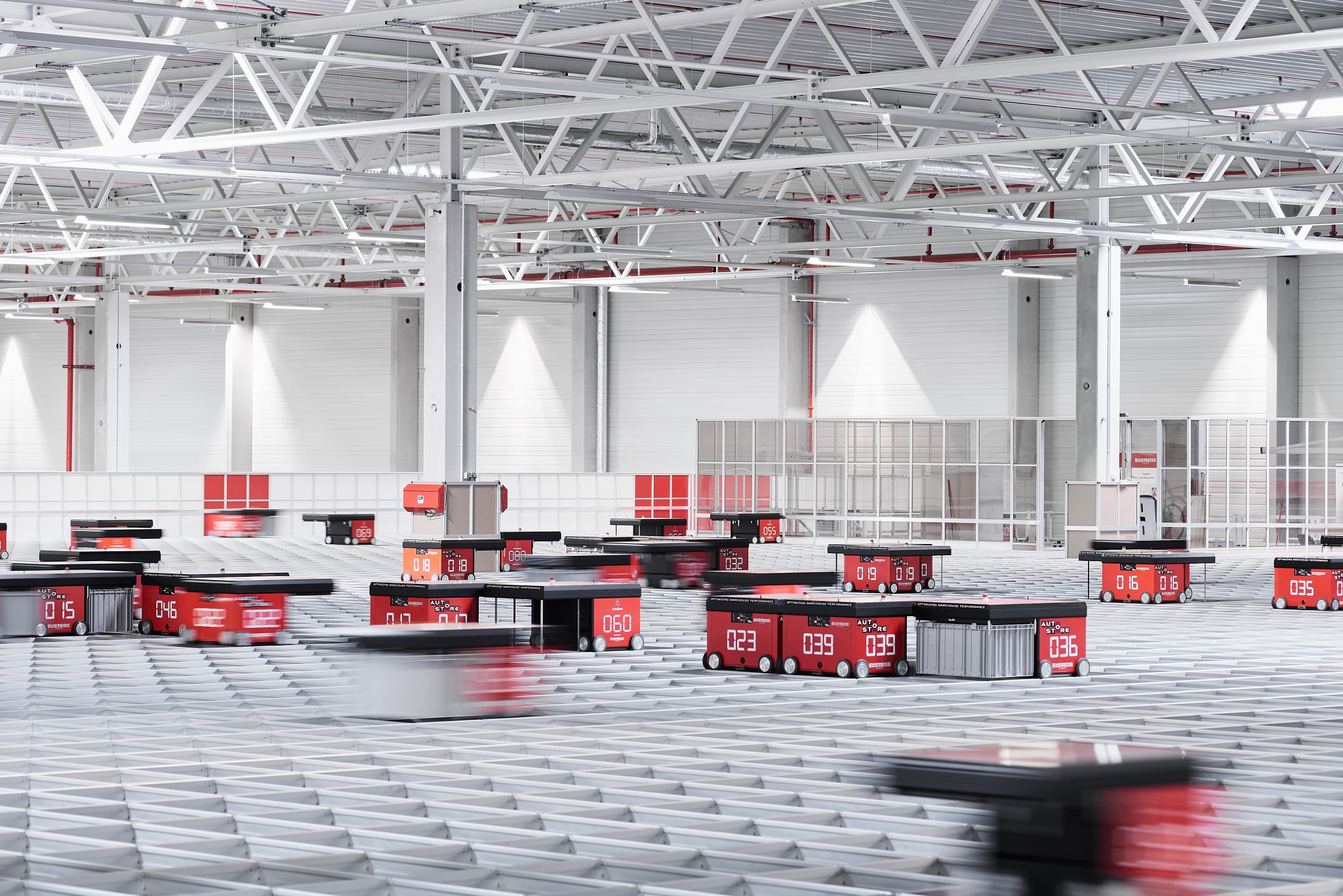 Robots desplazándose por encima de la rejilla de aluminio de un sistema de automatización de almacenes AutoStore