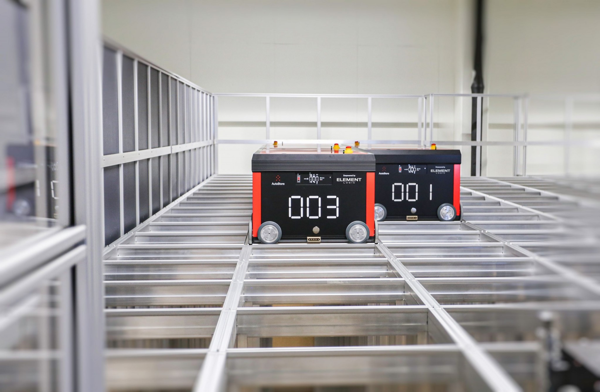 Dos robots AutoStore de Element Logic desplazándose por encima de la rejilla de aluminio de este sistema de automatización del almacén