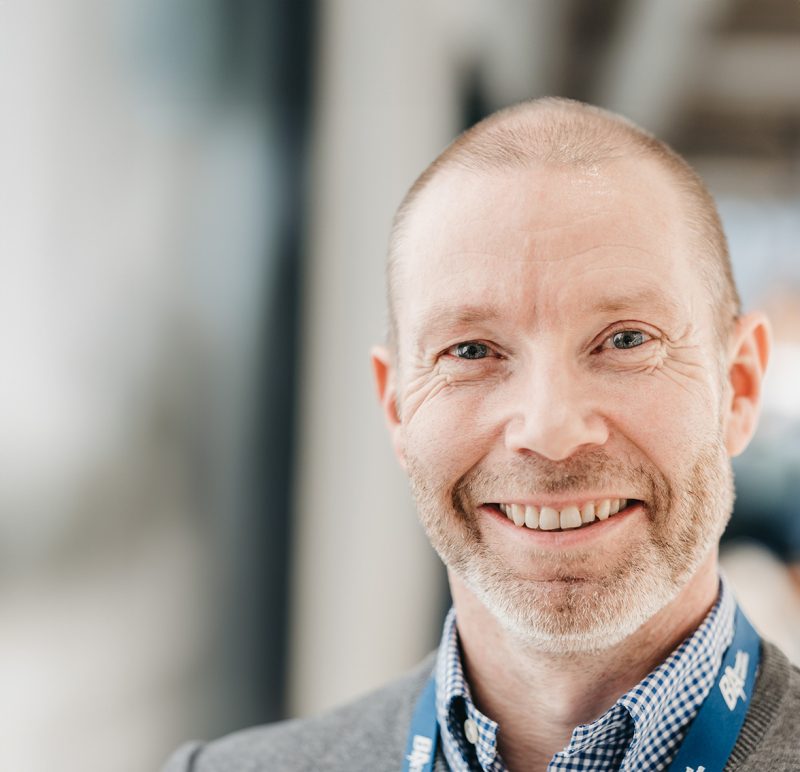 Rolf Inge Danielsen, Director de Logística de Berggaard Amundsen, sonriendo a la cámara en un ambiente de oficina con un collarín de identificación.